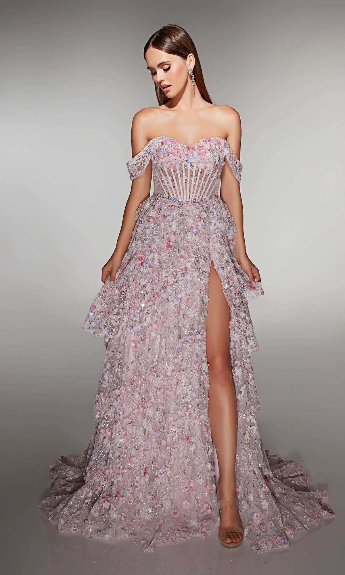 A woman wears the Long Prom Dress: Alyce 62186 in pink, featuring a strapless A-line design with high slit, sheer corset bodice, and 3D floral appliques, standing against a neutral background.